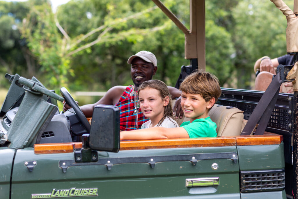 Children on safari in a safari vehicle with a Masai guide